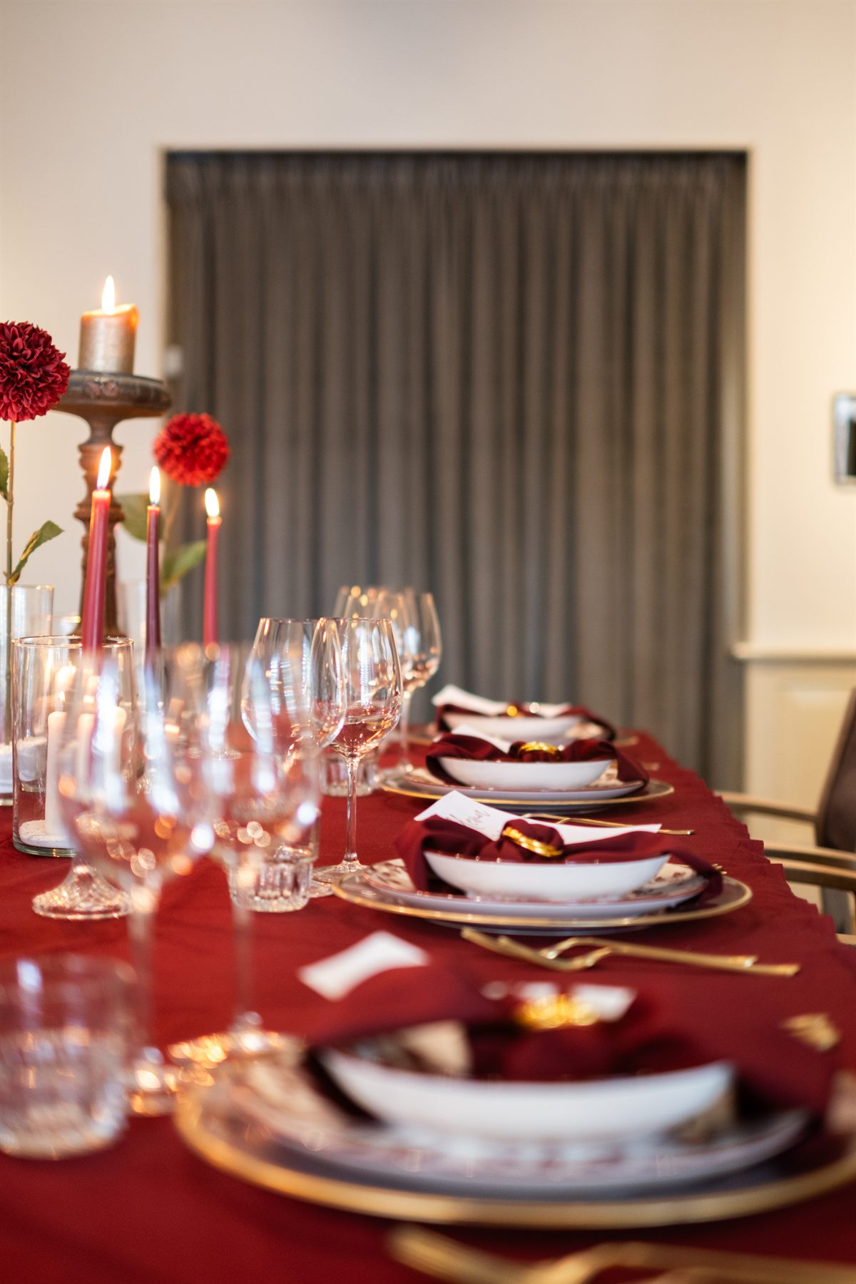 Lange dinertafel in bordeaux met bloemen en kaarslicht