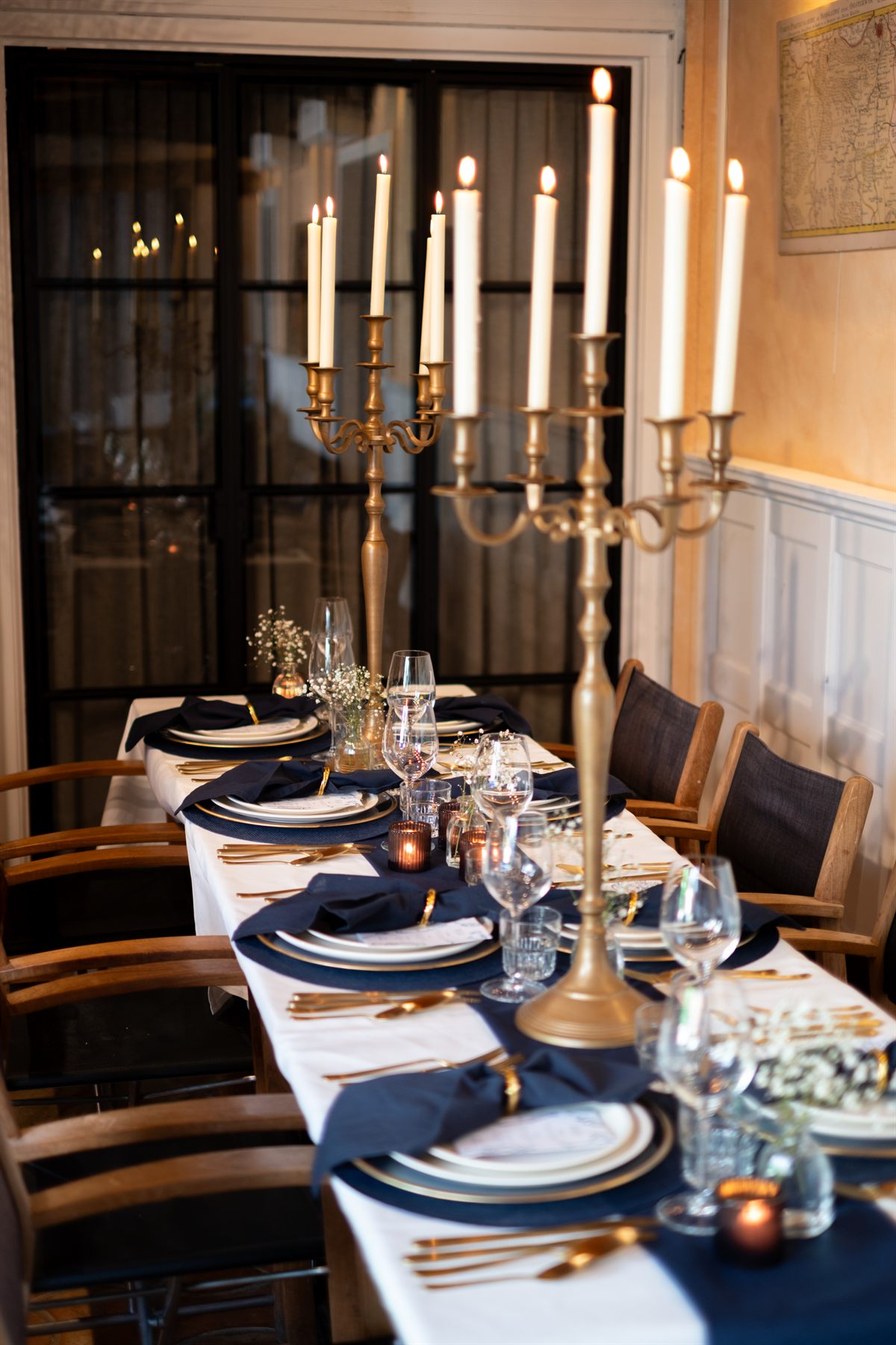 Gedekte dinertafel in donkerblauw en goud met hoge kandelaars