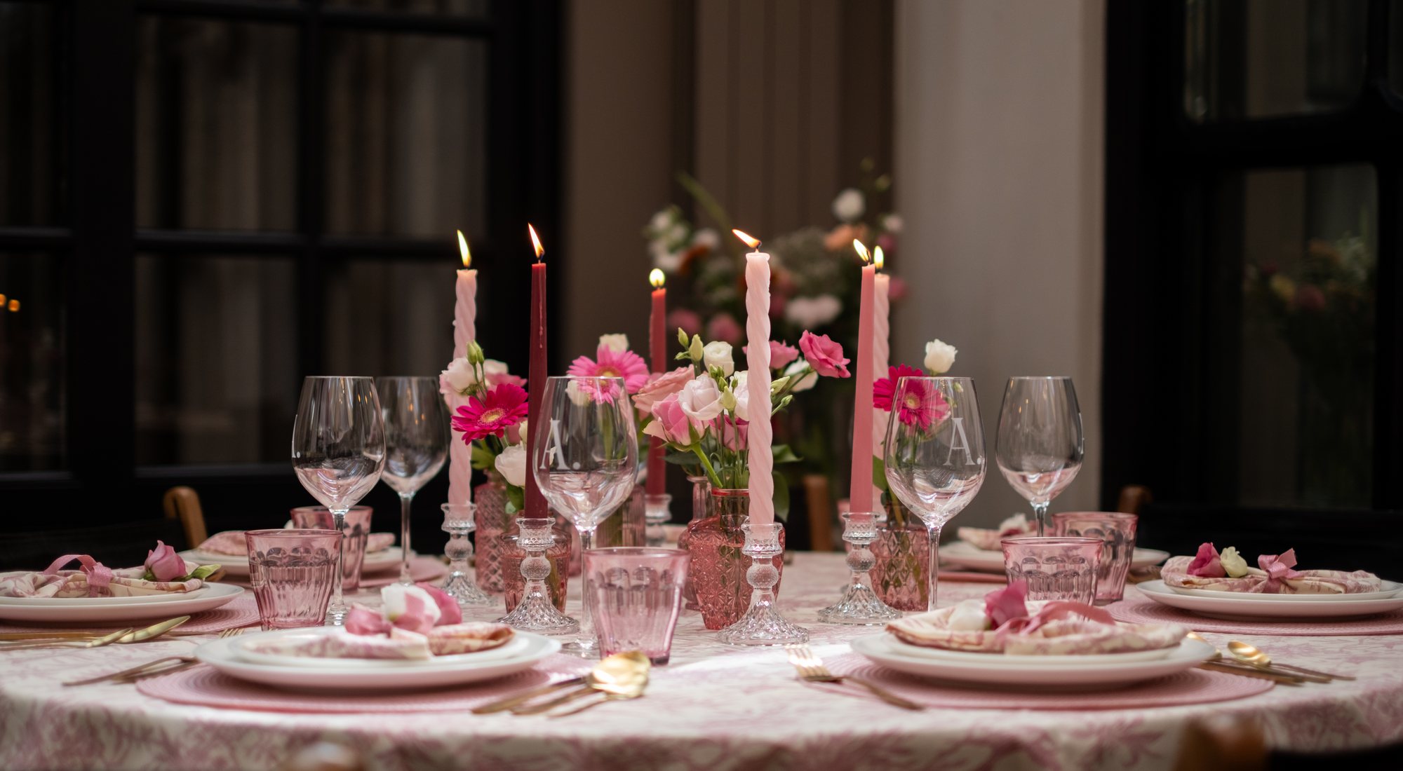 Romantisch gedekte tafel met roze bloemen, kaarslicht en gouden details